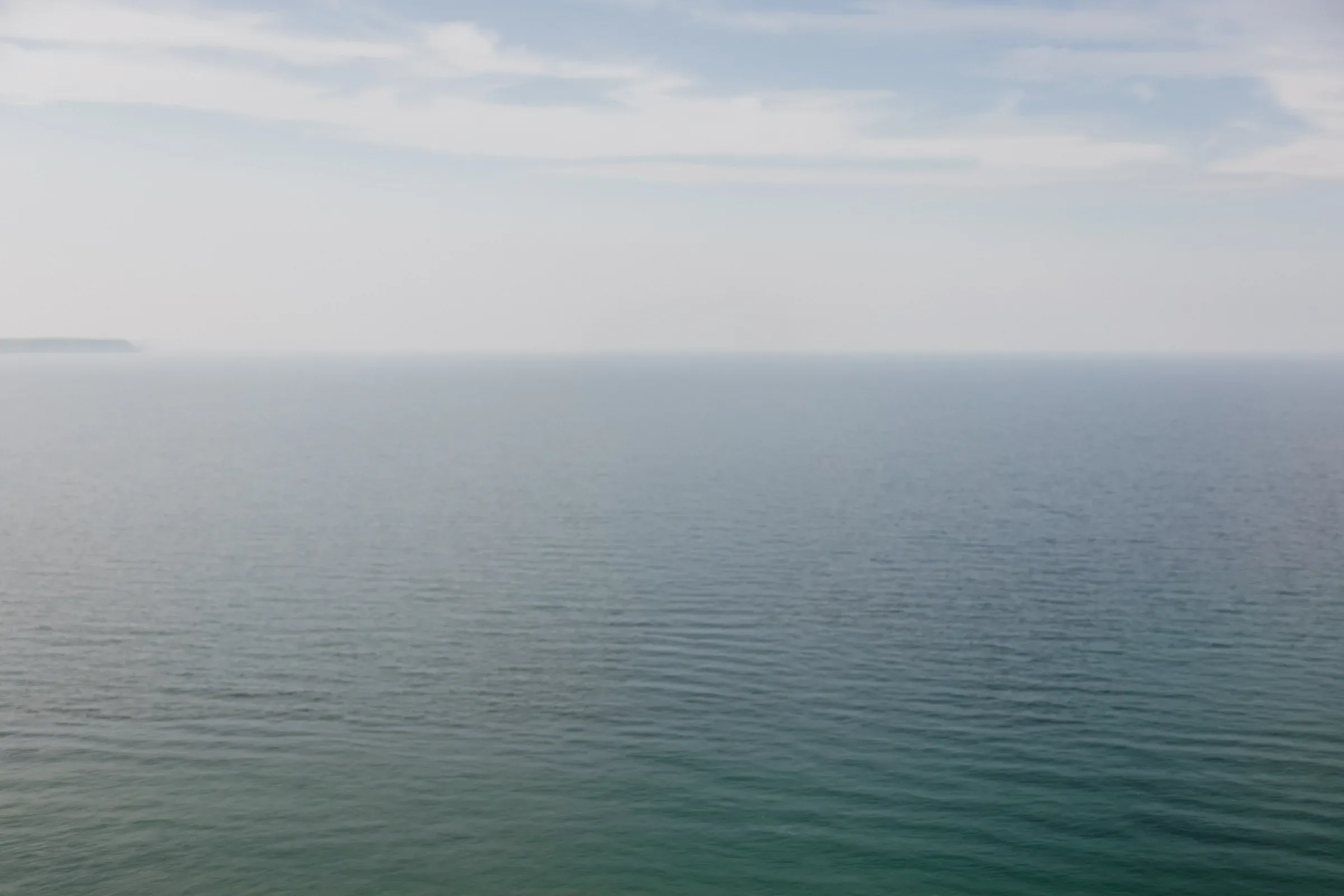 Blue water meeting a pale, cloudy horizon
